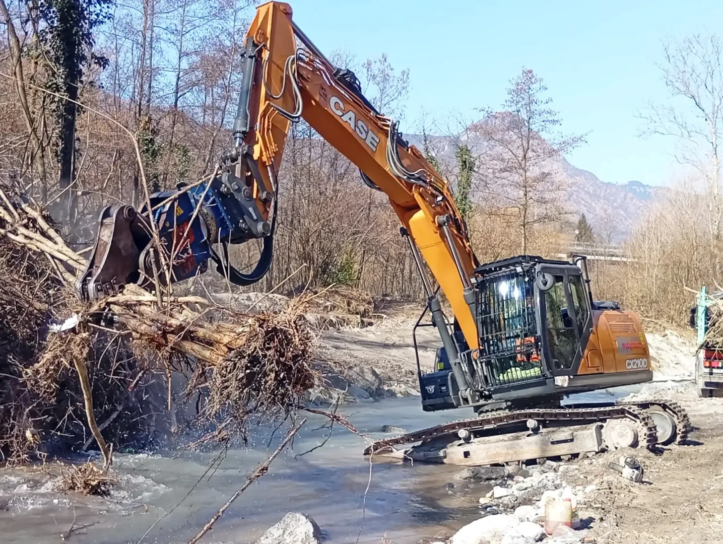 Opere fluviali con escavatore per sistemazione argini e manutenzione del fiume in area montana
