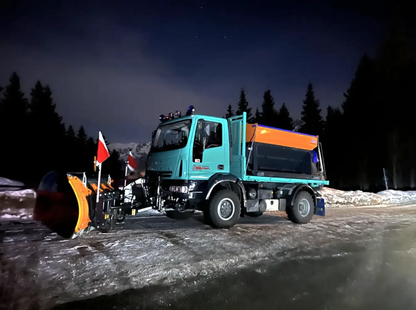 Camion spartineve in azione di notte per sgombero neve su strada in area montana